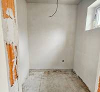 The space in the family house shows raw walls and a small window without flooring.