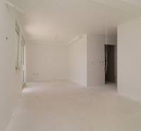 An empty space in a recreational apartment with white walls and cables on the ceiling.