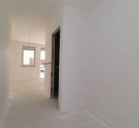 A hallway with light walls leading to a room in a vacation apartment.