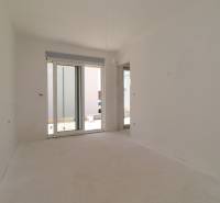 A bright room in a recreational apartment with a large window and an unfinished floor.