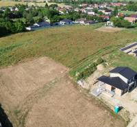 Construction of houses on Krátka Street in Alekšince with unfinished buildings and surrounding nature.