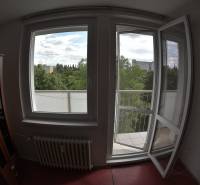 Interior of a 2-room apartment with a view of trees and buildings through an open window and balcony.