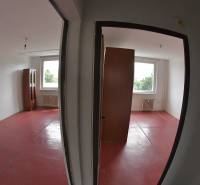 Two empty rooms with red flooring and radiators in a two-room apartment.