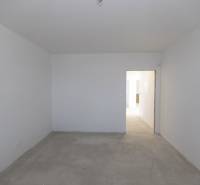 An empty room with a concrete floor and white walls in a family house.