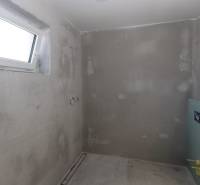 A concrete room under construction in a family house, with a small window and installation.