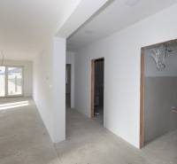A hallway in a family house with empty rooms and a large window at the end.