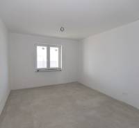An empty room in a family house with white walls and a window.