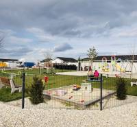 Playground in Galanta Košúty with climbing frames and a sandbox near family houses.