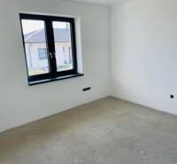 An unfurnished room in a family house with a window, overlooking the neighboring house.