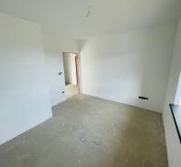An empty room with white walls and a concrete floor in a family house.