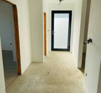 A hallway in a family house with a concrete subfloor and uninstalled lighting.