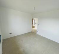 An empty room with white walls and an unfinished floor in a family house.