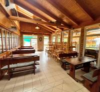 Wooden tables and chairs in dining areas with a brick wall and wooden ceiling.