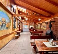 Interior of dining spaces with wooden benches, decorative paintings, and a brick fireplace.