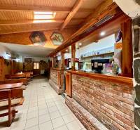 Interior of dining spaces with wooden benches, a bar, and decorative paintings on the walls.