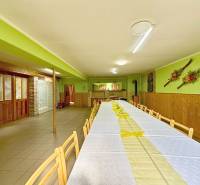 A long table with wooden chairs in a dining area with wooden paneling and decorations.