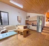 Interior of a gastro space with a kitchen unit, sofa, and wooden ceiling.