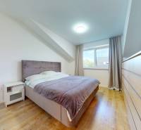 An attic bedroom with a bed, a dresser, and a window in a five or more room apartment.