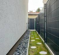 A narrow outdoor space with gravel next to a house in Bratislava - Podunajské Biskupice, Padlých hrdinov Street.