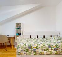 A children's room in a 5 or more room apartment with a table, chair, and a bed with a patterned bedspread.