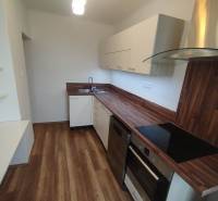 A kitchen unit with a wooden countertop in a 3-room apartment, white cabinets, and built-in appliances.