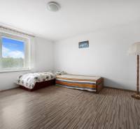 A bright room in a family house with a bed, a lamp, and a view outside.