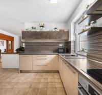 A family house kitchen with wooden cabinets, a dining area, and a window.