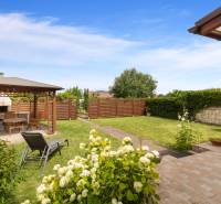The garden of a family house in Vinosady with a gazebo, a deck chair, and flowers.