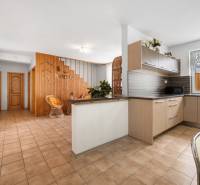 A kitchen with a dining area in a family house with wooden elements and ceramic tiles.