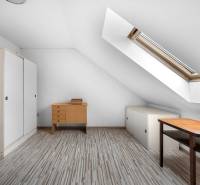 Attic room in a family house with a table and a wardrobe under the skylight.