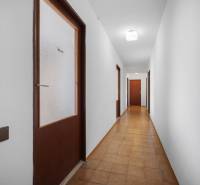 A hallway with brown doors and white walls, tiled floor in a family house.