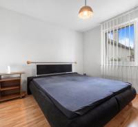 A bedroom in a family house with wooden floors, a dark bed, and a nightstand.