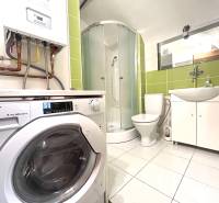 Bathroom with a shower, toilet, and washing machine in a 3-room apartment.