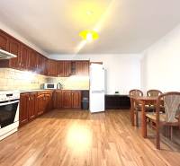 A spacious kitchen in a 3-room apartment with light wooden furniture and a dining table.