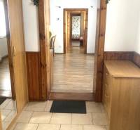 The hallway of a 3-room apartment with wooden paneling and a mirror leads to other rooms.