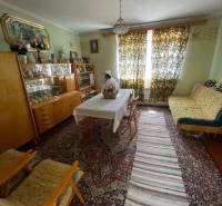 A traditionally furnished living room in a family house with carpets and curtains.