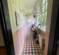 The interior of a porch in a family house with a tiled floor and a window wall.