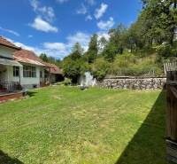 A family house in Horná Súča with a lawn, trees, and a clear sky.