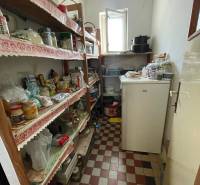 A pantry in a family house with shelves and a checkered pattern floor.