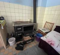 In the interior of the family house, there is a tiled stove with an oven and a chair next to it.