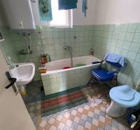 A bathroom in a family house with a bathtub, sink, toilet, and laundry on a line.