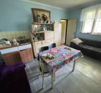 A kitchen in a family house with a blue wall, furniture, and a floral tablecloth.