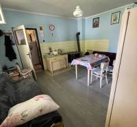 The kitchen of the family house with a tiled stove, table, and sofa is cozily furnished.