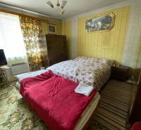 Bedroom in a family house with a bed, carpet, and vintage decoration.