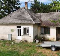 Older family house in Kolárovo with an extension, garden, and a trailer in front of the house.