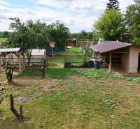 The garden of a family house in Kolárovo with wooden shelters and greenery in the surroundings.