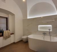 A bathroom with a freestanding bathtub in a 2-room apartment with a lighted shelf.