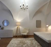 Bedroom in a 2-room apartment with a chandelier, armchair, and bed, in soft color tones.