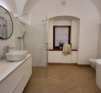 A bathroom in a 2-room apartment with a sink, shower, bathtub, and window.