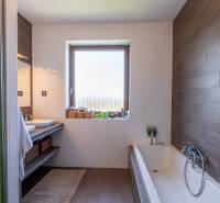 A bathroom in a family house with a bathtub, a sink, wooden paneling, and baskets.